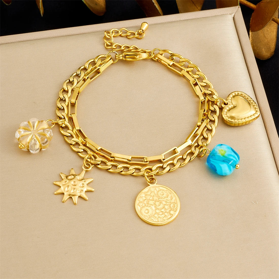 Gold-tone double-layer bracelet with heart and sun charms, turquoise bead and crystal flower