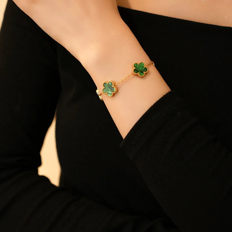 Gold flower bracelet with green enamel clover charms on wrist