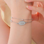 Silver-tone Virgin Mary bracelet with cross charm and oval pendant, worn on wrist