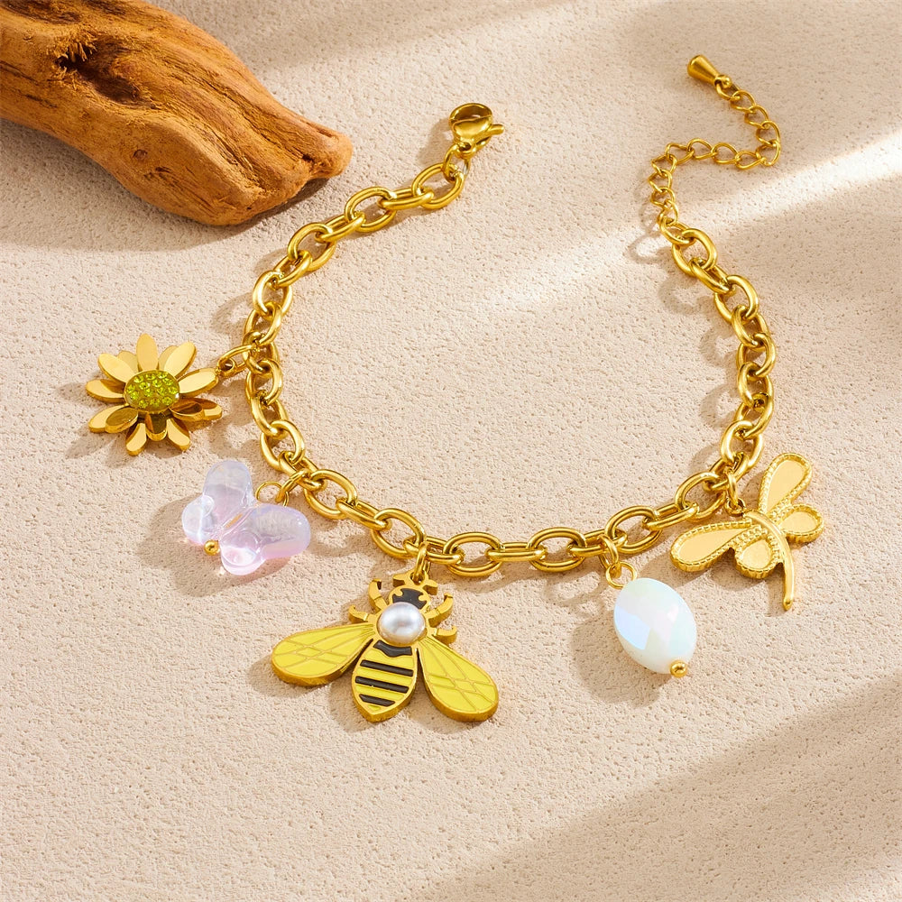 Gold-tone charm bracelet with sun flower, bee, pearl, and white bead drops
