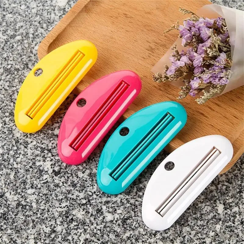 Toothpaste tube squeezer dispenser set in yellow, pink, teal, and white with metal strips