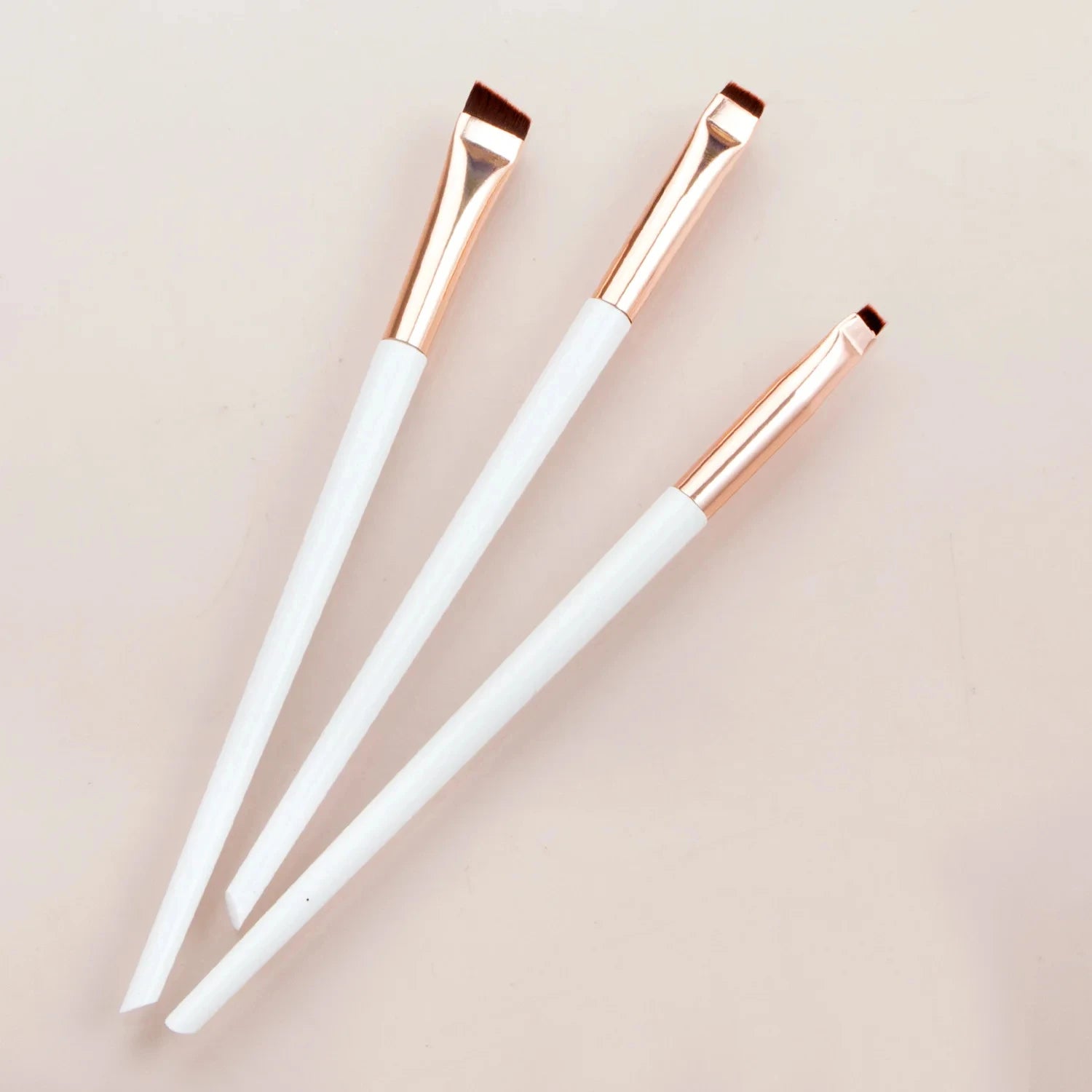 Eyeliner and eyebrow makeup brushes, three white handles with copper bristle tips