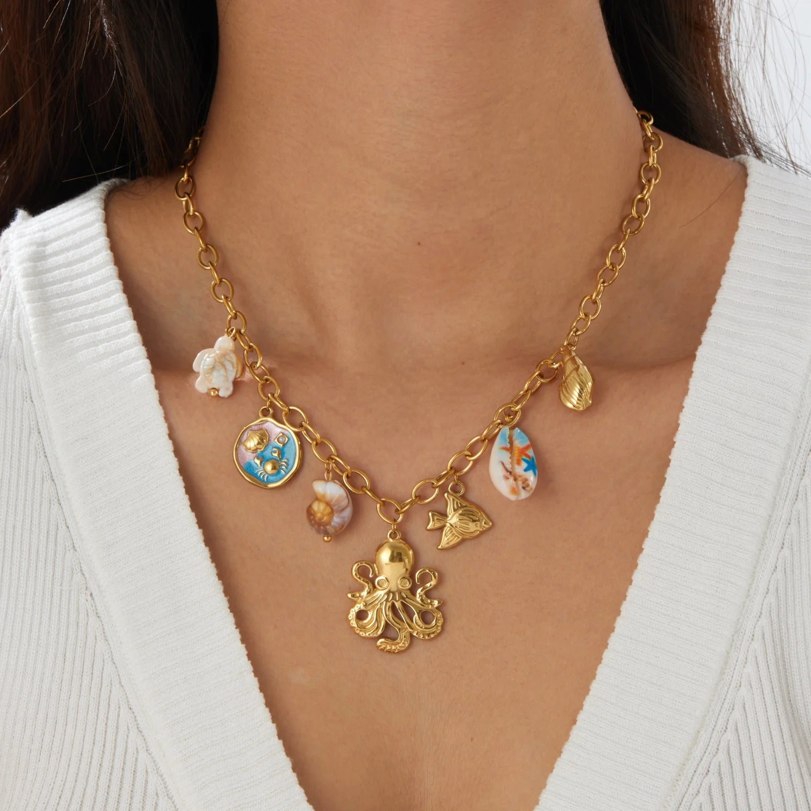 Gold-tone necklace with octopus charm and blue enamel shell drop, on chain links.