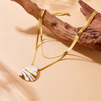 Gold-tone pendant necklace with white tiger stripe teardrop charm, long chain