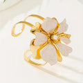 Flower cuff bangle bracelet with gold-tone band and white enamel flower with pearl center.
