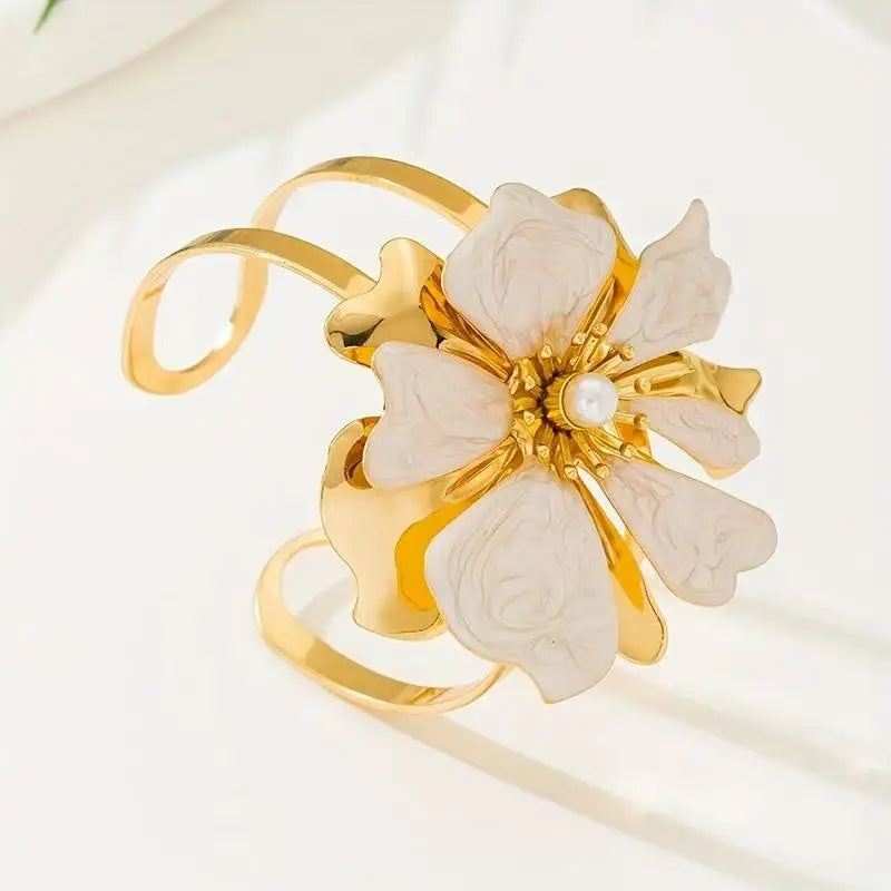 Flower cuff bangle bracelet with gold-tone band and white enamel flower with pearl center.