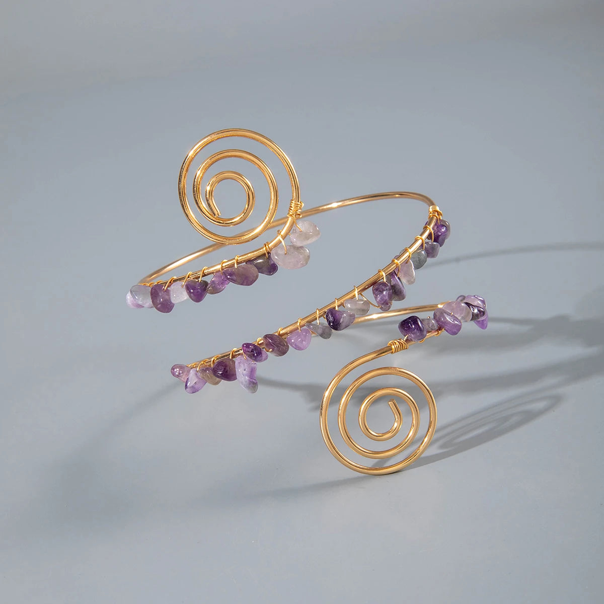 Gold-tone upper arm bracelet with spiral charm and purple and clear stone bead strands