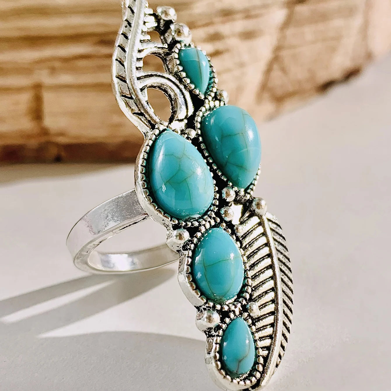 Turquoise cabochon boho ring with leaf border, feather motif, and silver-tone band
