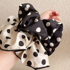Cotton scrunchies in cream and black polka dots with white dots, held in hand
