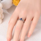 Silver evil eye ring on hand with small blue center stone and sparkling crystal edges