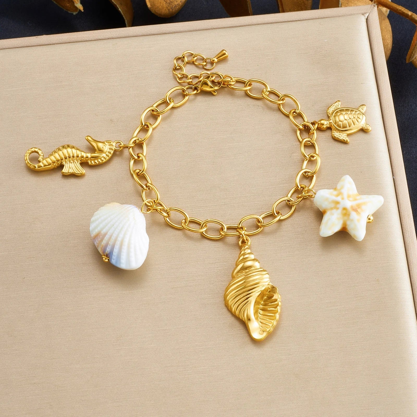 Gold-tone shell charm bracelet with seashell, fish, turtle, and star charms