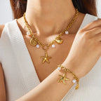 Gold-plated pendant necklace with starfish and shell charms, pearl beads, and link details