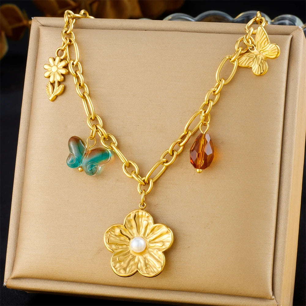 Gold-tone multi-pendant necklace with turquoise butterfly, red teardrop, and flower charm