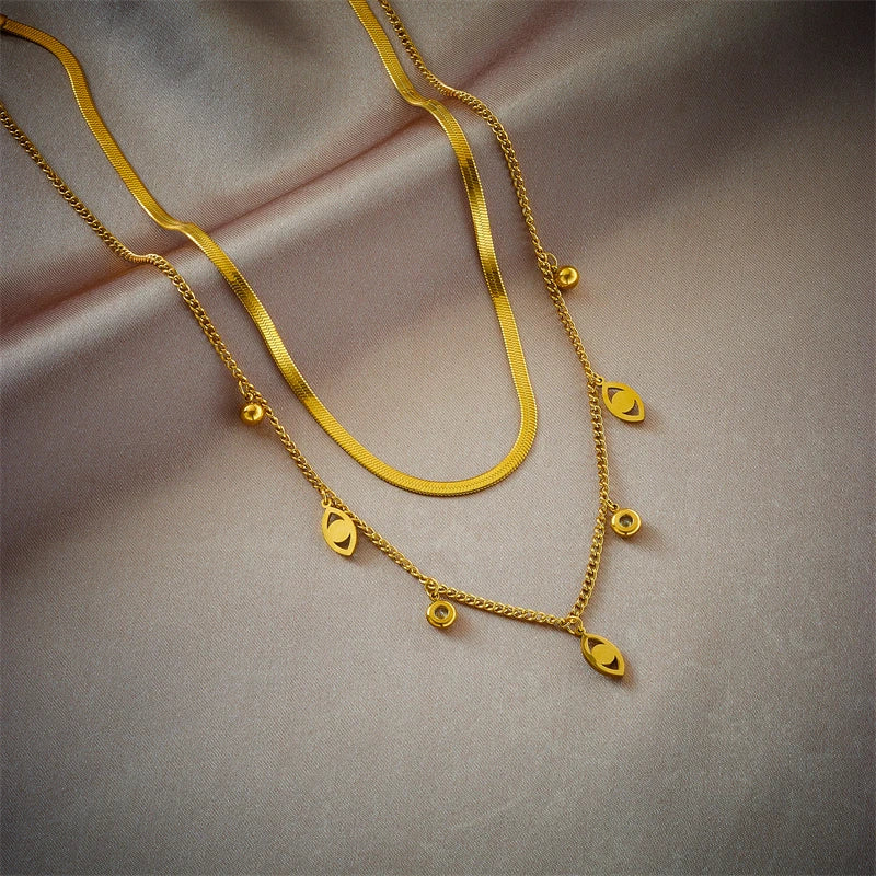 Gold-tone double-layer snake chain necklace with heart-shaped charm accents and dangling beads