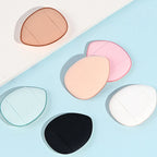 Assorted teardrop finger puff sponges: light blue, pink, tan, white, and black.