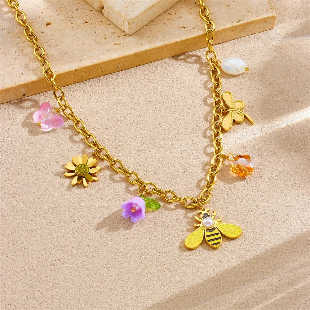 Gold-tone charm necklace with bee, flower, pearl, and pastel resin details