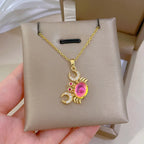 Gold-tone crab pendant necklace with pink center stone and red and clear rhinestone details.