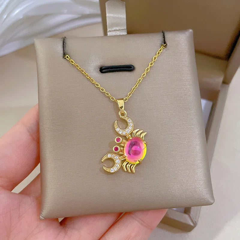 Gold-tone crab pendant necklace with pink center stone and red and clear rhinestone details.