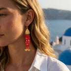 Gold-tone koi charm drop earrings with layered red beads worn by model.