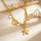 Gold-plated necklace charms on display: starfish pendant, shell charm, and white pearl beads