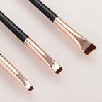 Eyeliner and eyebrow makeup brushes, angled brown bristle heads on rose-gold handles