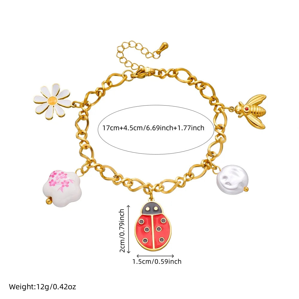 Gold-tone ladybug charm bracelet with flower, bird, and pearl drops; size-mark diagram