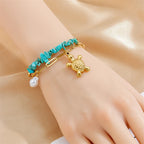 Turquoise beaded gold necklace on hand with turtle charm and pearl drop