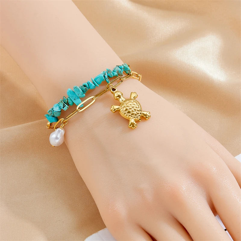 Turquoise beaded gold necklace on hand with turtle charm and pearl drop