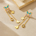 Gold-tone butterfly drop earrings with blue enamel wings, flower and teardrop crystal charms