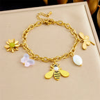 Gold-tone charm bracelet with bee, flower, and white petal/pearl accents