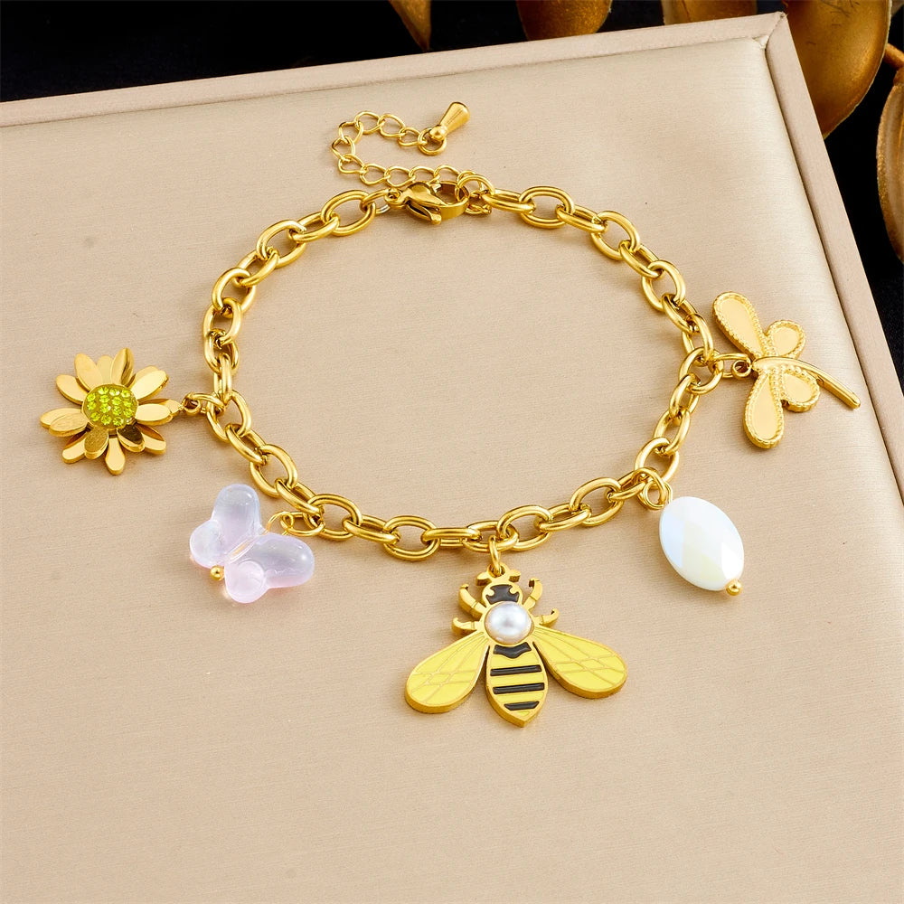 Gold-tone charm bracelet with bee, flower, and white petal/pearl accents