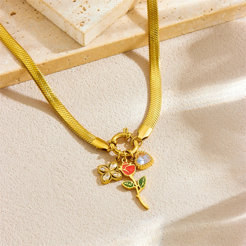 Gold-tone pendant necklace with rose charm and red enamel heart on snake chain
