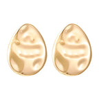 Textured gold teardrop stud earrings with smooth raised hammered detail