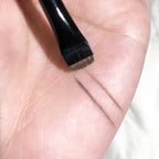 Eyeliner and eyebrow makeup brush with angled brown bristles on a black handle