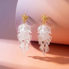 Pair of gold starfish pendant jellyfish earrings with clear translucent jelly charms.