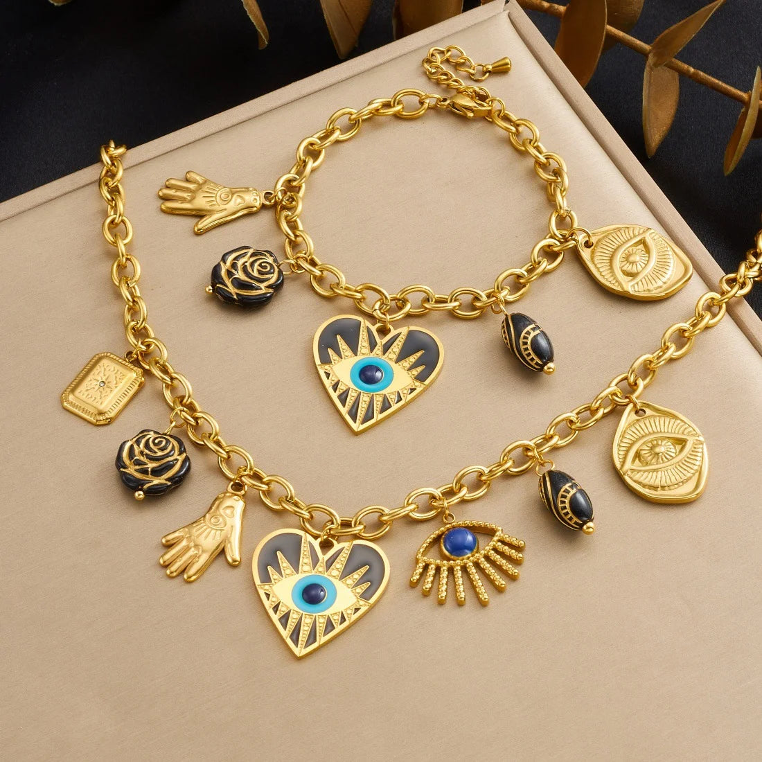Gold evil-eye hamsa charm jewelry set with heart, hand, and eye pendants