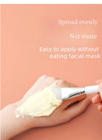 Silicone face mask brush spreading pale cream on hand, white silicone head with chrome ferrule