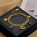 Gold-tone evil-eye double bangle bracelet with blue teardrop and eye pendants