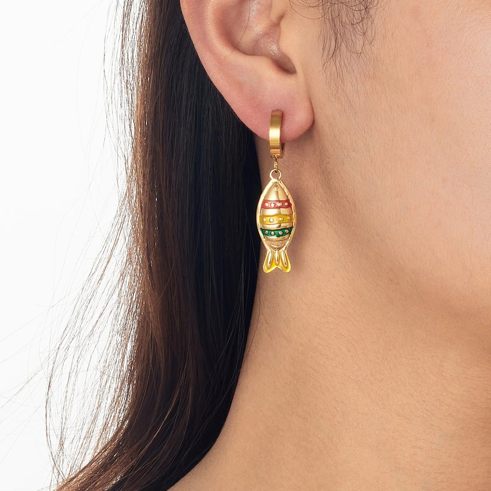 Fish enamel huggie hoop earring on model, gold-tone with striped red and green fish charm