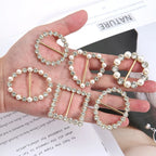 Assorted pearl and rhinestone knot scarf brooch clips in hand, gold-tone pins