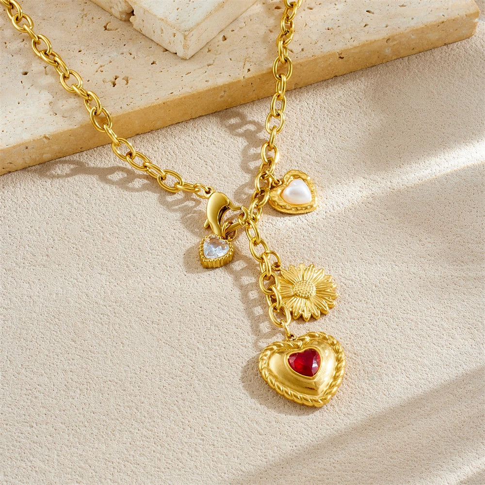 Gold tone pendant necklace with red heart charm, small white pearl hearts, and flower charm