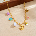 Gold enamel pendant necklace with heart, bow, and daisy flower charms on a gold chain