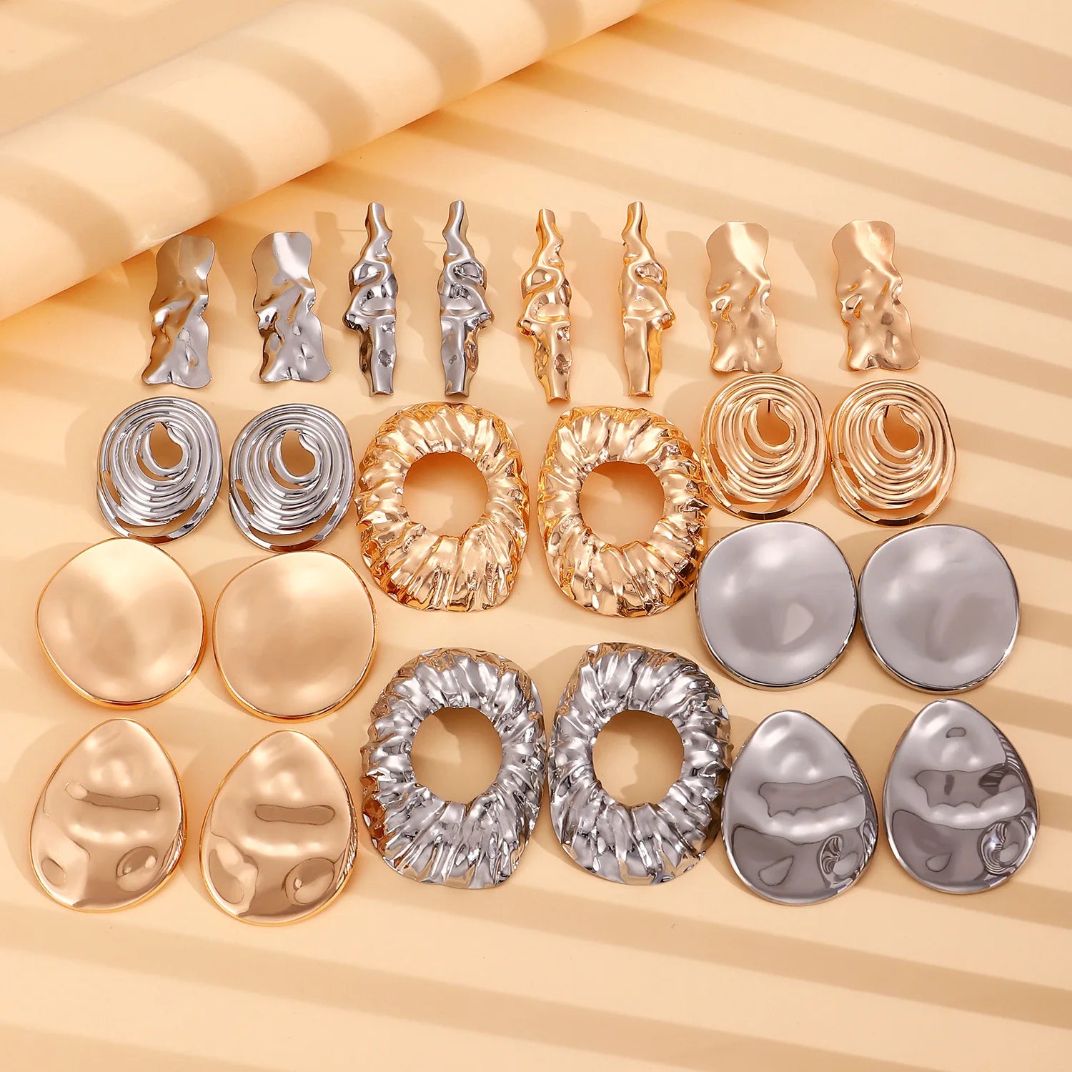 Assorted wrinkled gold and silver-tone drop earrings laid out on a display