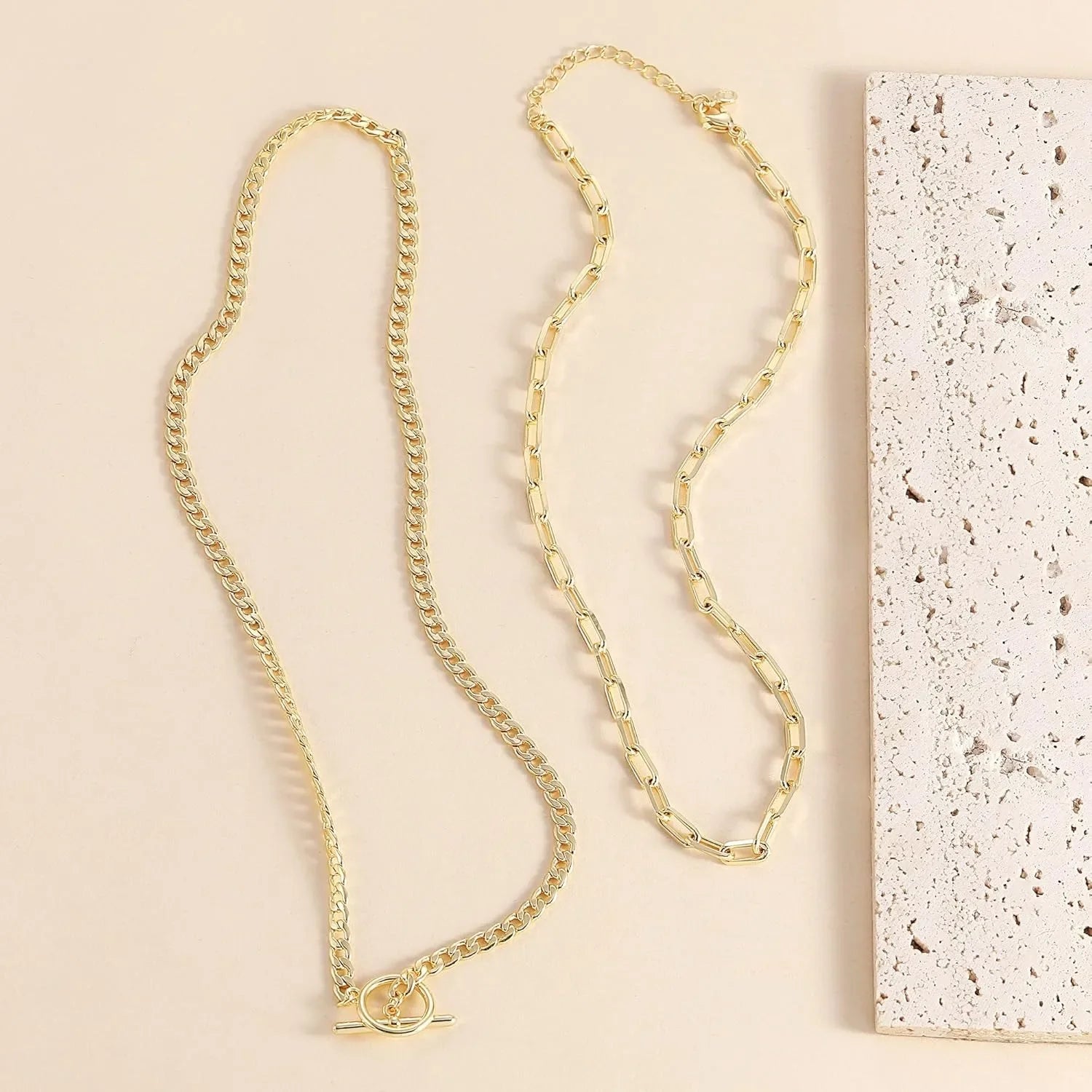 Gold layered chain necklace set shown with oval connector at the front