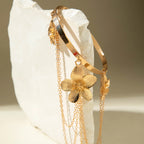Gold cuff bracelet with dangling flower charm and long chain fringe