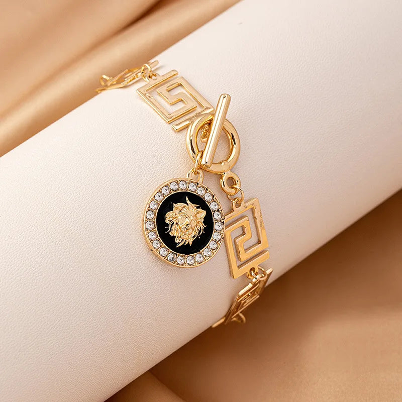 Gold embossed chain anklet with round lion medallion and dangling Greek-key links