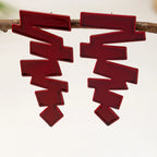 Geometric stud earrings in deep red with layered zigzag shapes on the ear