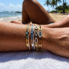 Gold plated evil-eye bangle bracelets with blue eye motifs and small link accents