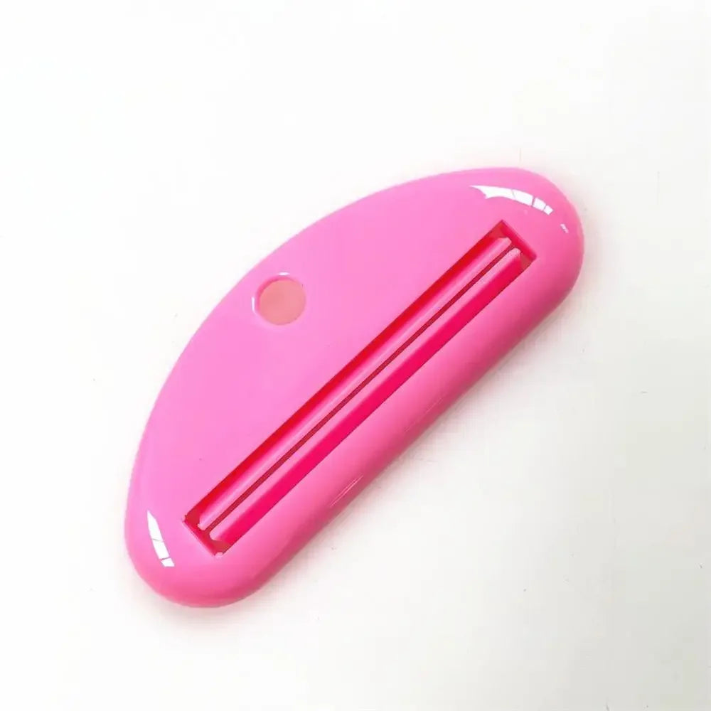 Pink toothpaste tube squeezer dispenser with slotted metal insert and hanging hole