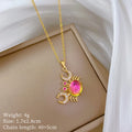 Gold-tone crab pendant necklace with pink center stone and rhinestone hoop charm accents.